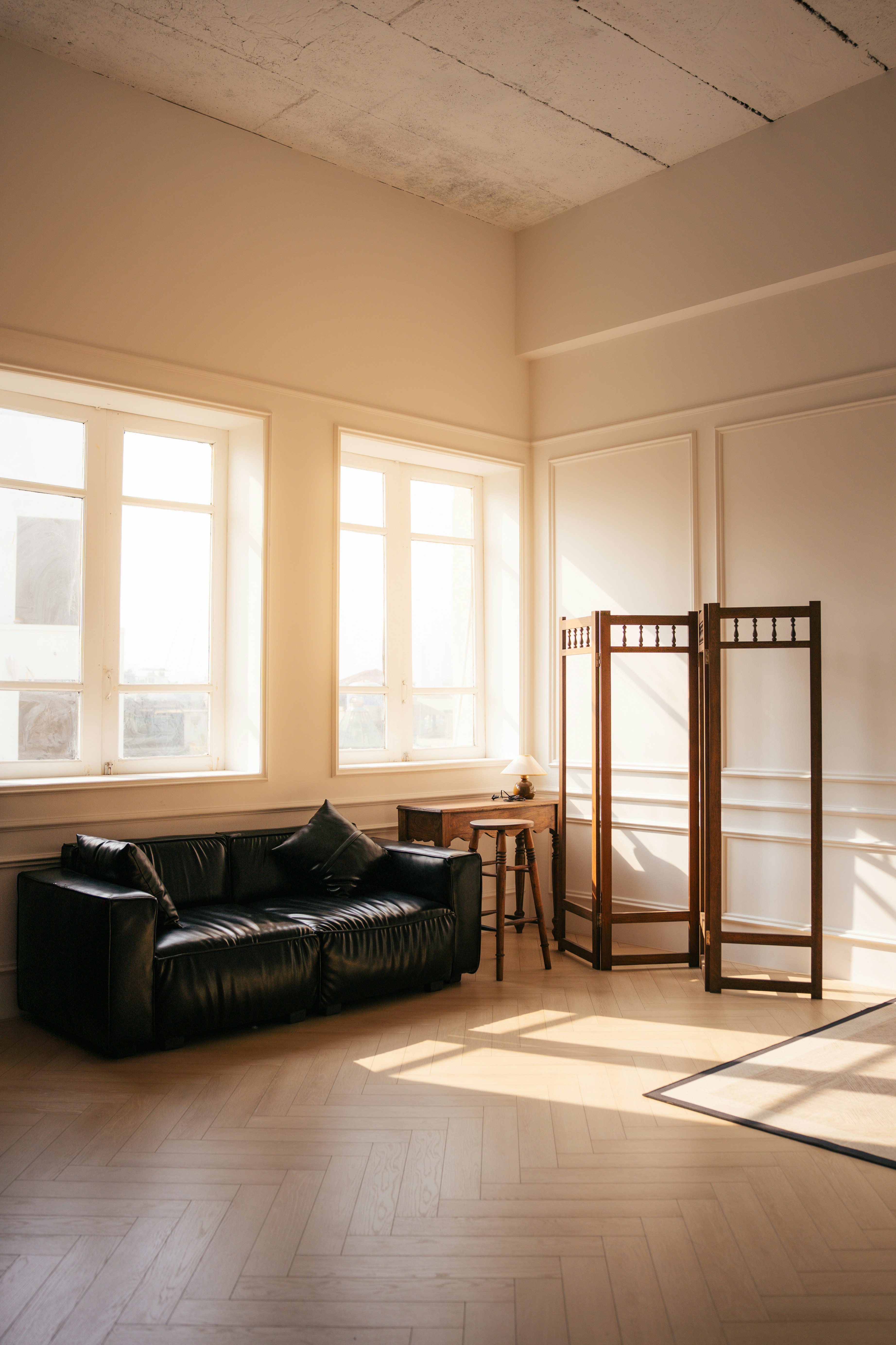 Sunlit room with a black sofa and a folding screen