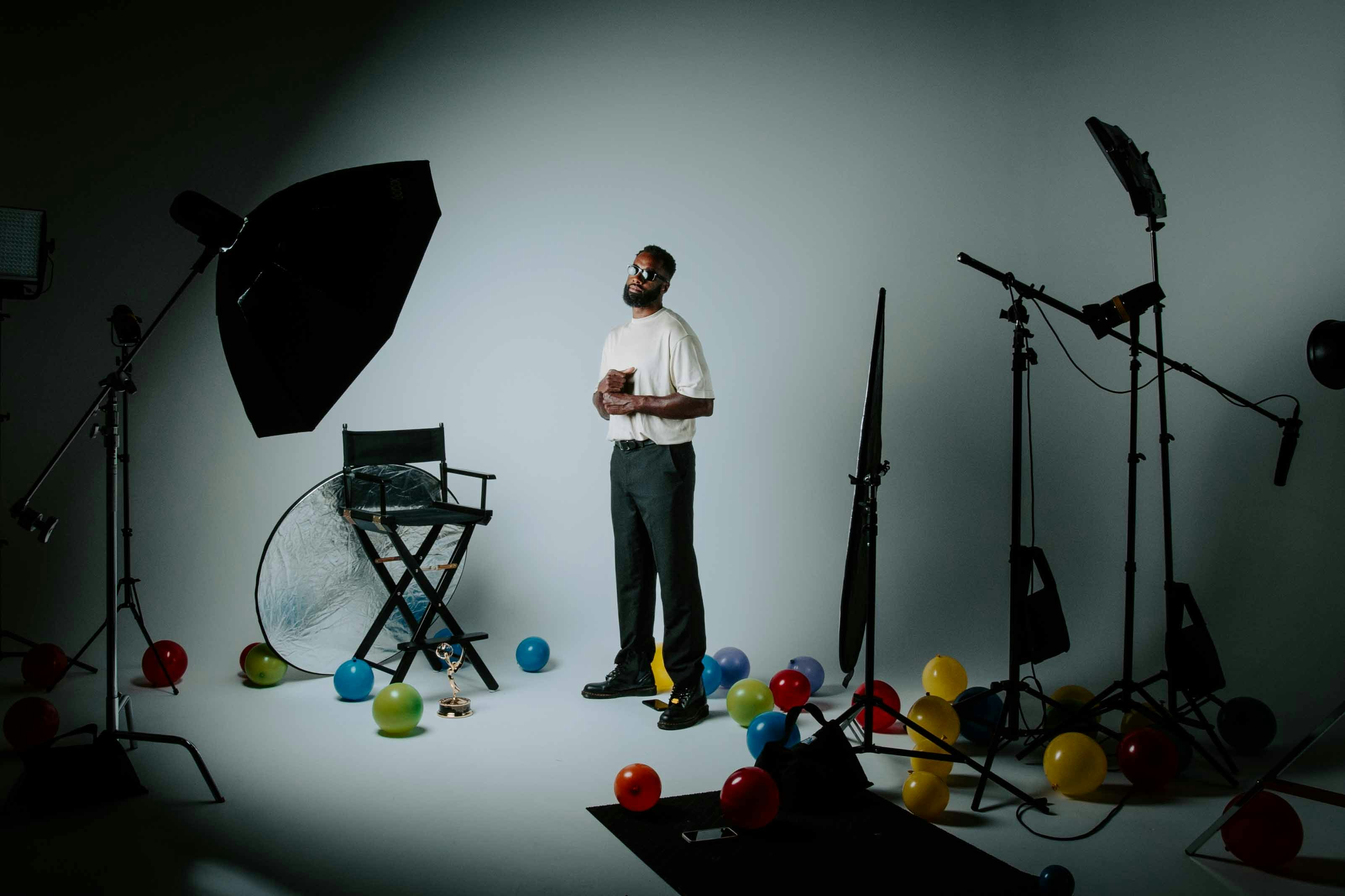 Man standing in a studio surrounded by lights and a paper sweep